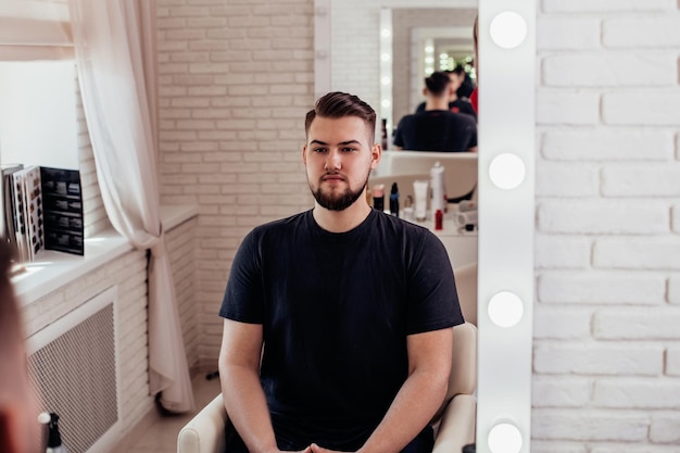 Uomo bruna con taglio di capelli alla moda su sfondo da barbiere