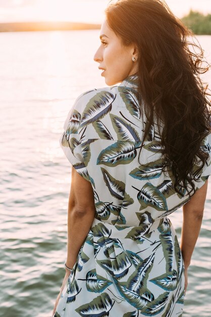 brunette meisje in een elegante zomeroutfit en strohoed in de stralen van de zon op natuurwandeling