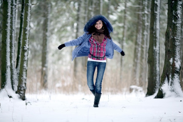 Brunette meisje loopt in een besneeuwd bos.