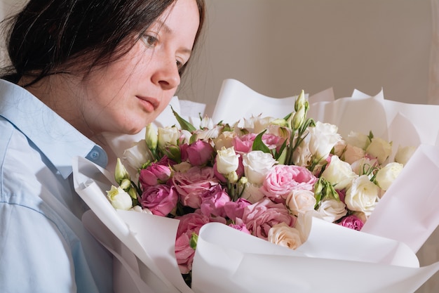 Brunette meisje met een groot boeket roze rozen en geniet op bed