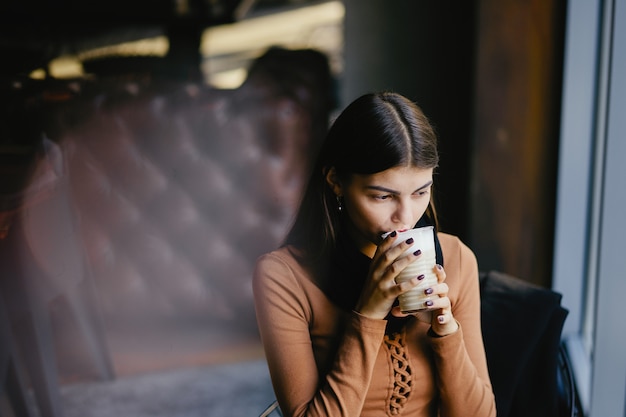 brunette meisje met haar telefoon terwijl het drinken van koffie in een restaurant