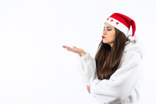 Brunette meisje met Kerstmis met een witte achtergrond, met een kerstmuts met sterren, gooien en kussen naar links, kopieer ruimte