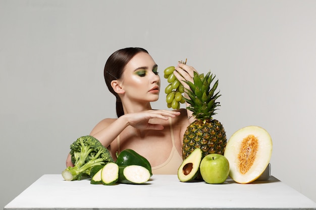 brunette meisje met make-up poseren met fruit