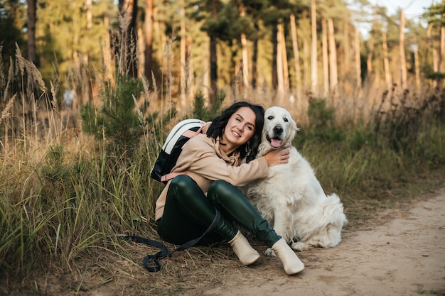 Brunette meisje met witte golden retriever hond op het bospad