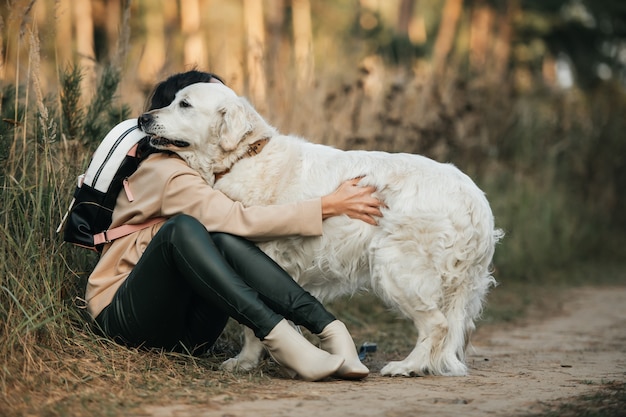 brunette meisje met witte golden retriever hond op het bospad