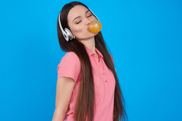 Brunette meisje vormt met kauwgom geïsoleerd.