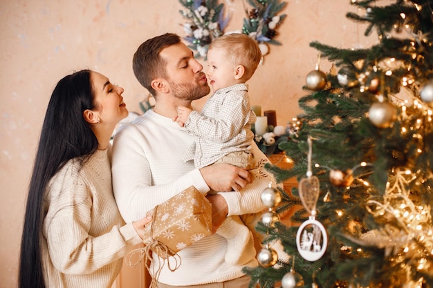 Brunette moeder vader en zoontje staan in de buurt van de kerstboom