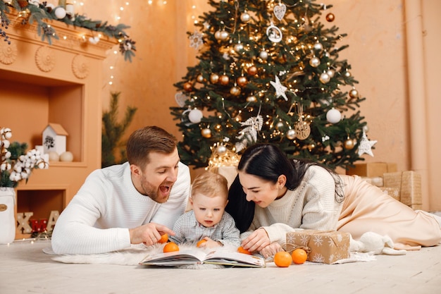 Brunette mother father and little son sitting near Christmas tree