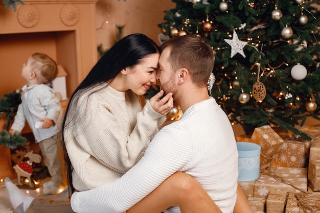 Brunette mother father and little son sitting near Christmas tree