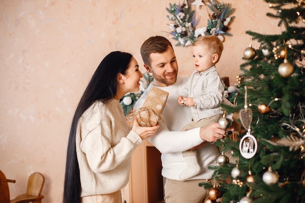 Brunette mother father and little son standing near Christmas tree