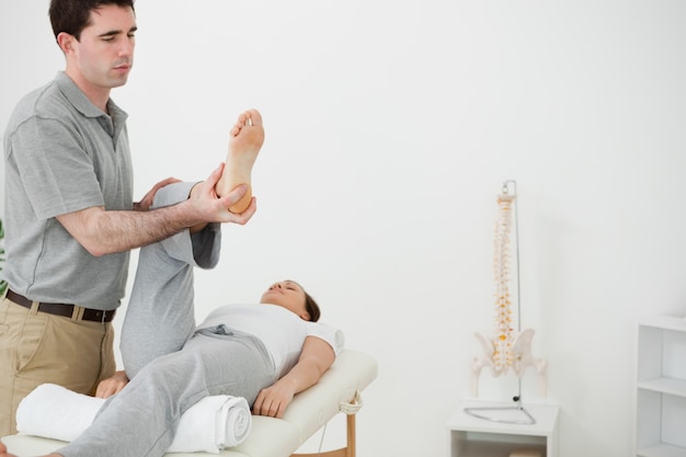 Photo brunette physiotherapist manipulating the leg of a woman