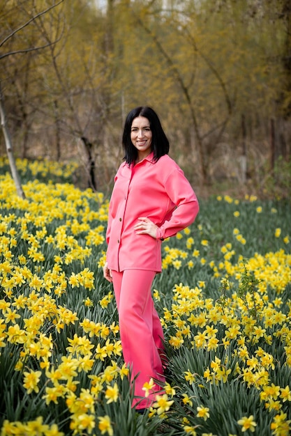 Foto una bruna in abito rosa tra i narcisi che crescono in giardino