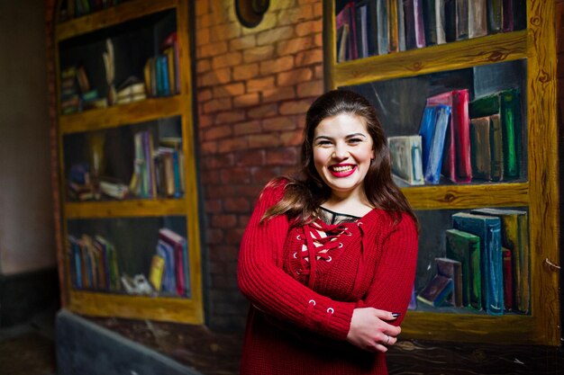 Brunette plus size model against wall like library.