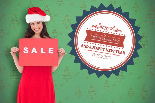 Brunette in red dress holding sale sign against green christmas tree pattern