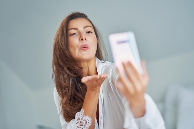 Brunette sexy meisje op bed met telefoon