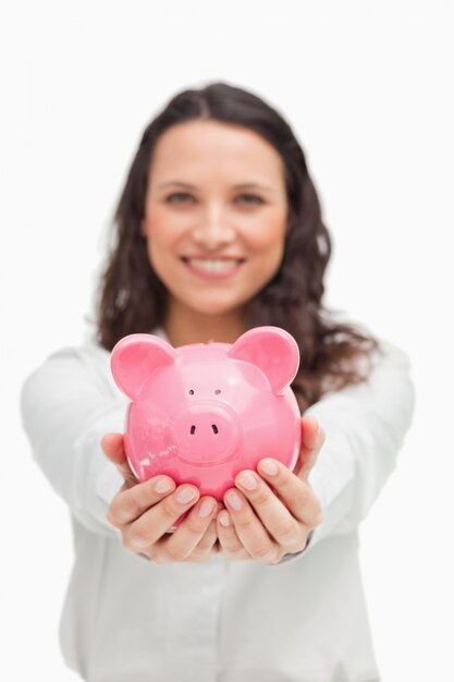 Brunette showing a piggy bank 