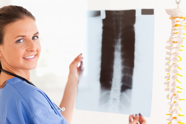 Photo brunette smiling doctor with a stethoscope and a x-ray