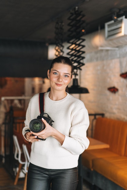 Brunette smiling young woman photographer working with her camera in cafe