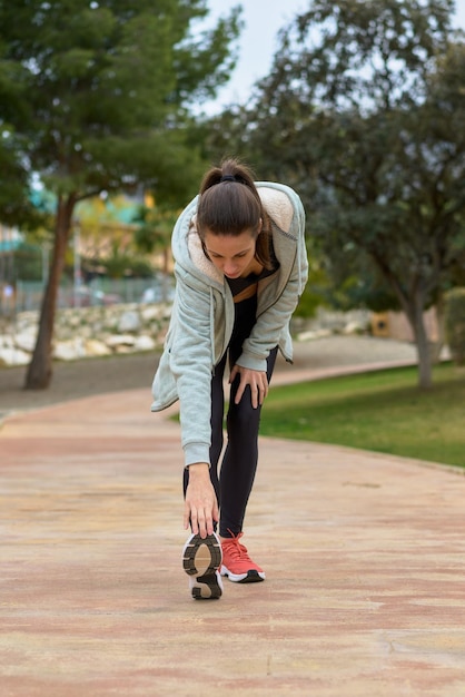 Brunette sportvrouw die zich uitstrekt in park