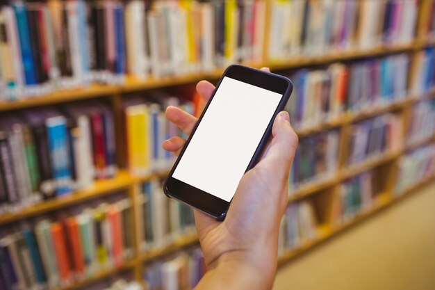 Brunette student using her smartphone in library