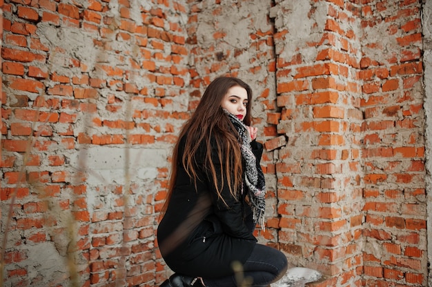 Brunette stylish casual girl in scarf against brick place.