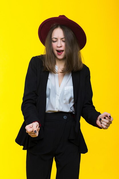 Brunette in a suit and hat on a yellow background