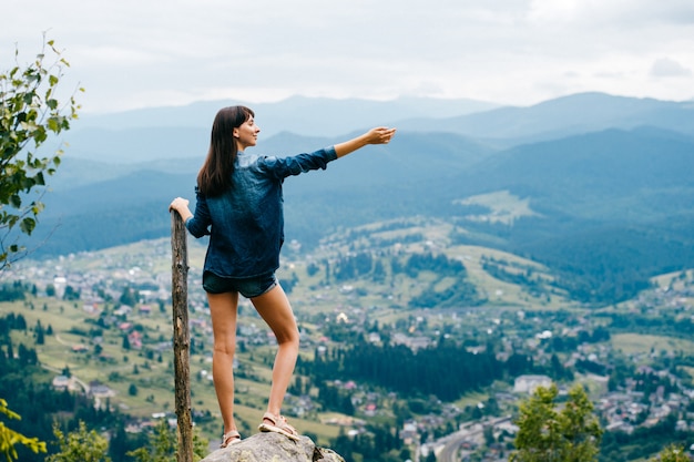 Brunette teen girl posing on top of mountain in summer