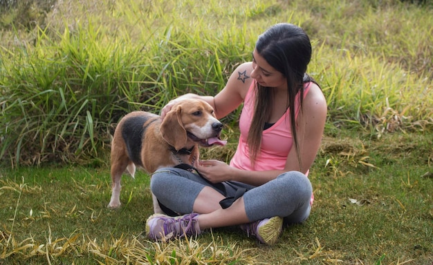 Brunette teenager with beagle dog in the park outdoors