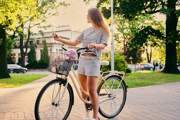 Brunette vrouw in een park op een fiets selfie maken met slimme telefoon.