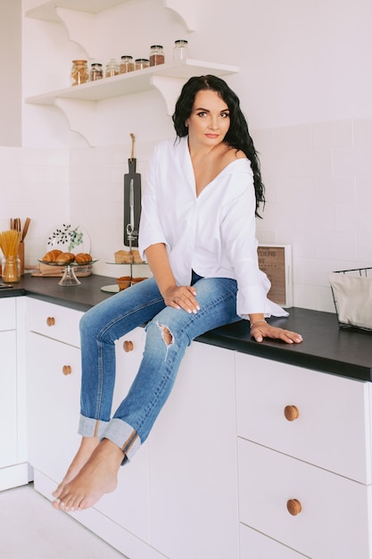 brunette vrouw in wit overhemd en jeans in de keuken