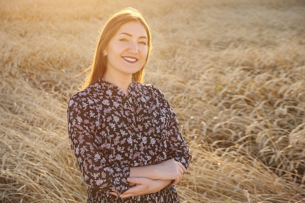 Brunette vrouw staat in een tarweveld zonlicht, copyspace