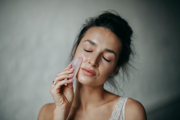 Brunette vrouw van 30 jaar doet gezichtsmassage met een gouache schraper