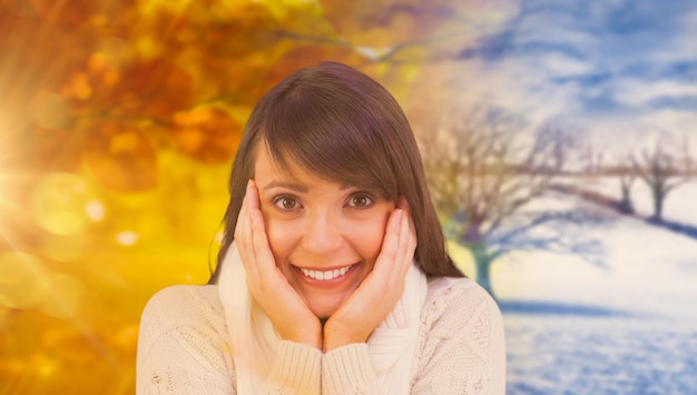 Brunette in winter clothes smiling at camera against autumn turning to winter