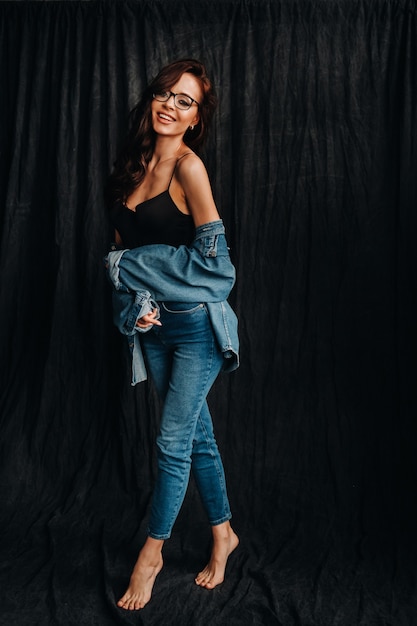 a brunette with long hair and glasses poses