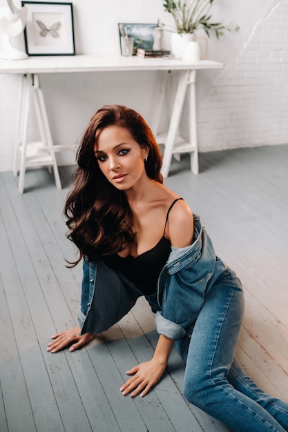 brunette with long hair poses sitting on the floor