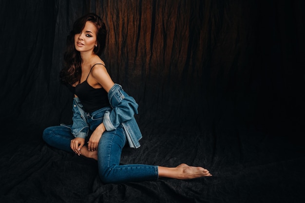 a brunette with long hair poses sitting on the floor