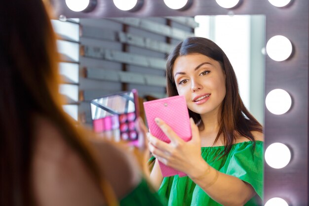 Brunette woman applying make up for a evening date