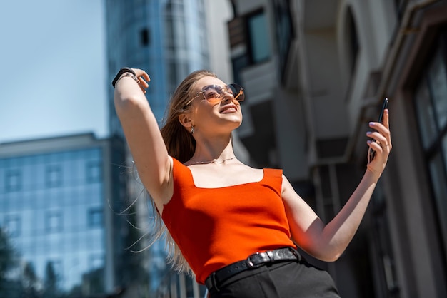 A brunette woman in branded clothes orders a taxi through a smartphone app