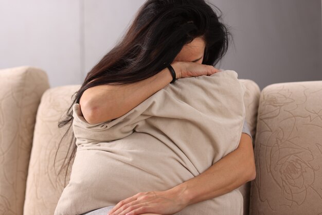 Brunette woman burying her head in pillow. Help with depression concept