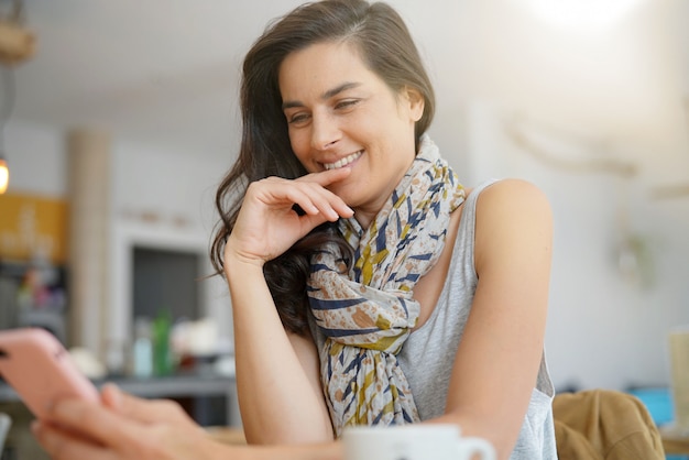 Brunette woman in coffee shop using smartphone