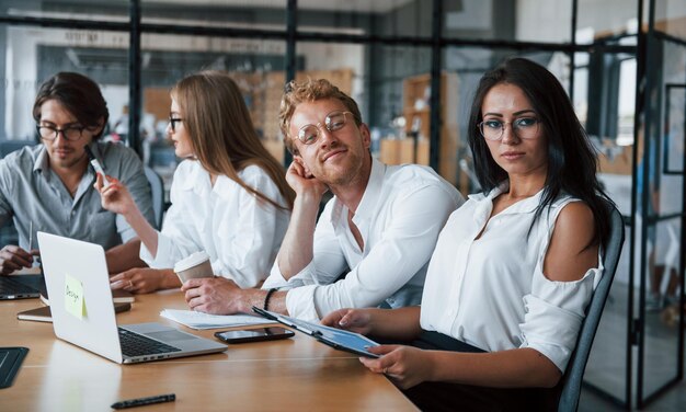 Foto donna bruna davanti ai dipendenti giovani uomini d'affari in abiti formali che lavorano in ufficio