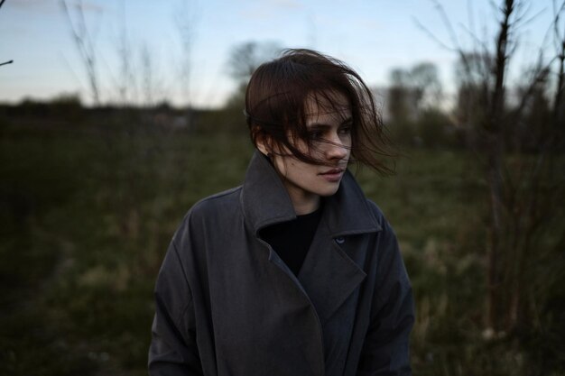 Brunette woman in a gray coat walks on the windy day