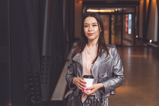 Brunette woman holding takeaway coffee