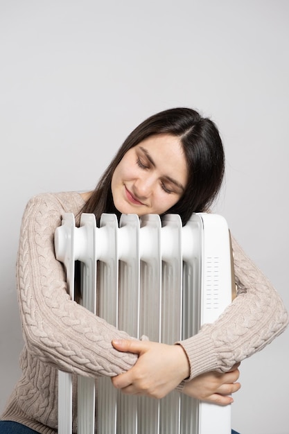 A brunette woman hugs an electric oil heater