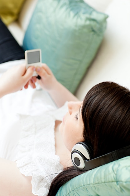 Brunette woman listening music lying on a sofa