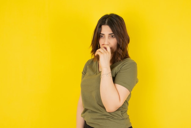 Brunette woman model standing and posing against yellow wall