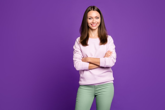 Brunette woman in pastel sweater posing against the purple wall