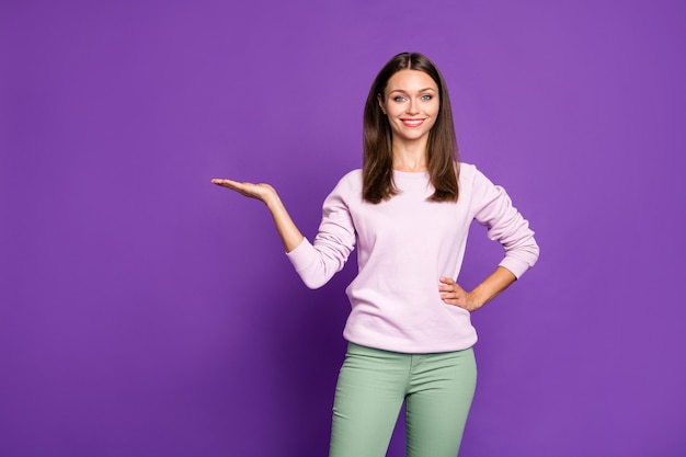 Brunette woman in pastel sweater posing against the purple wall