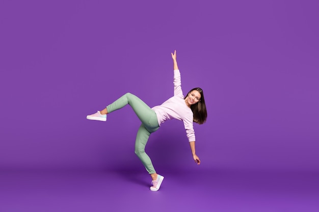 Brunette woman in pastel sweater posing against the purple wall