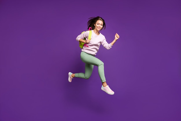 Brunette woman in pastel sweater posing against the purple wall